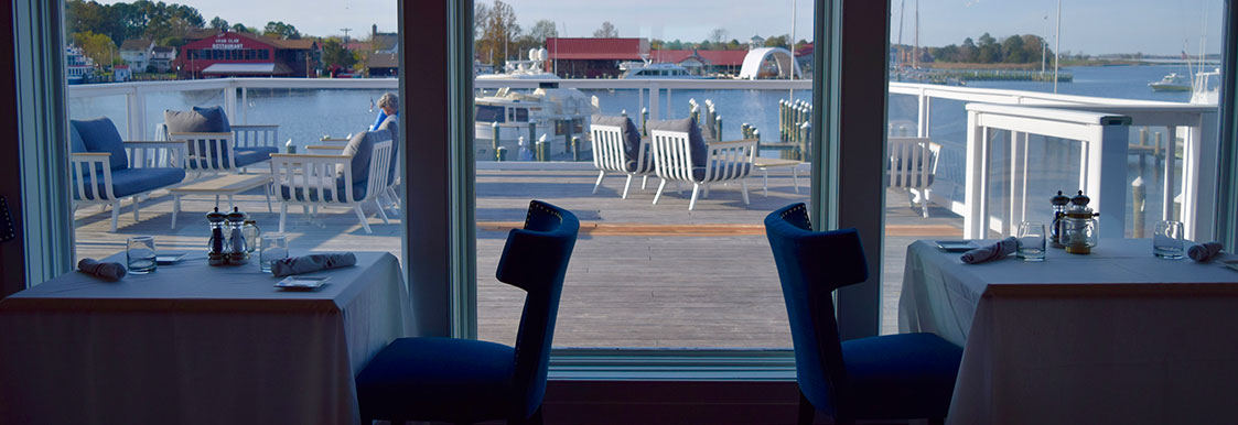 Dining room inside of Harbour Lights restaurant with water view with blue chairs and white table cloths
