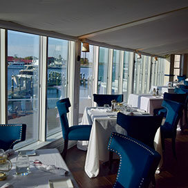 Dining room inside of Harbour Lights restaurant with blue chairs and white table cloths